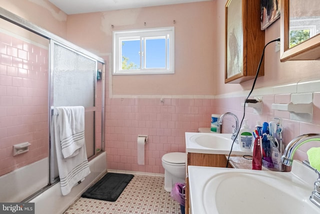 full bathroom with toilet, combined bath / shower with glass door, tile walls, vanity, and tile patterned flooring