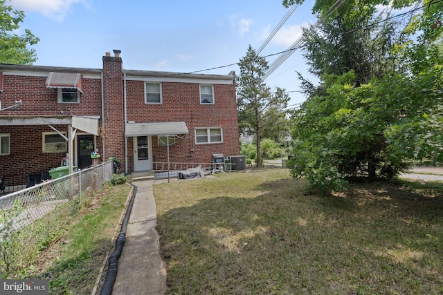 back of property featuring a lawn and central air condition unit