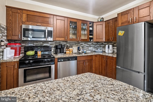 kitchen featuring light stone counters, decorative backsplash, and appliances with stainless steel finishes