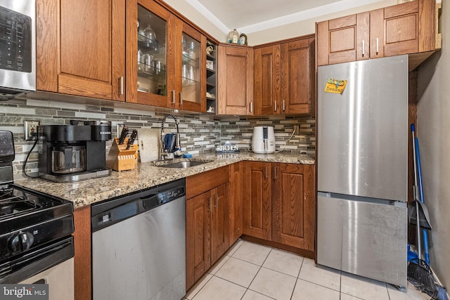 kitchen featuring appliances with stainless steel finishes, backsplash, light tile patterned floors, and light stone countertops