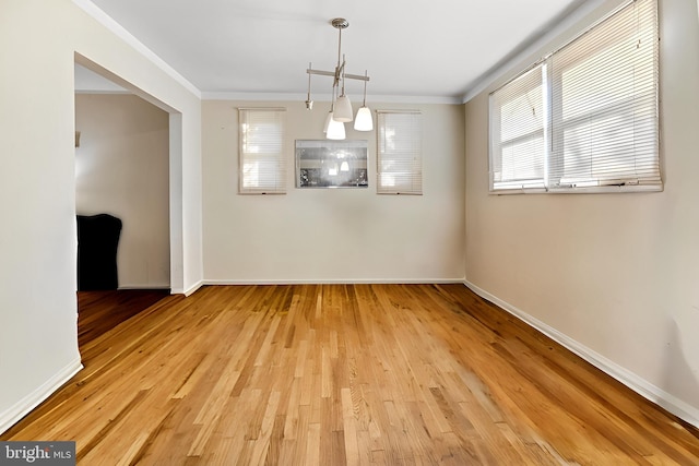 unfurnished dining area with ornamental molding and light wood-type flooring