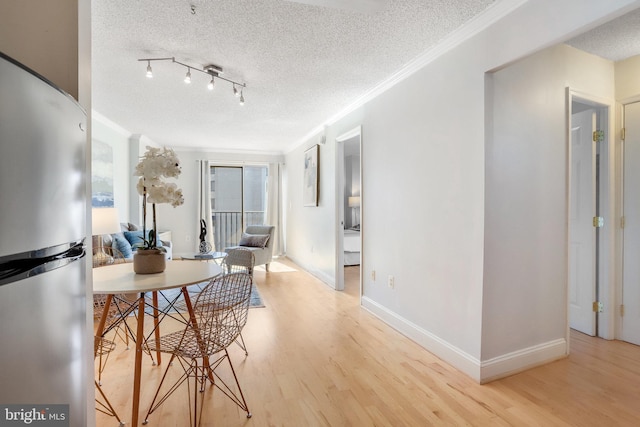 dining space featuring ornamental molding, a textured ceiling, and light hardwood / wood-style flooring