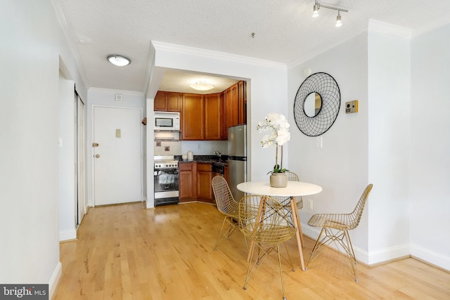 kitchen with ornamental molding, stainless steel appliances, and light wood-type flooring