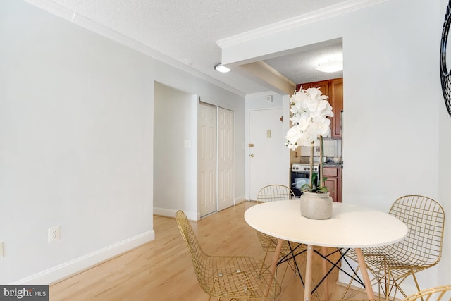 dining room with crown molding, light hardwood / wood-style flooring, and a textured ceiling