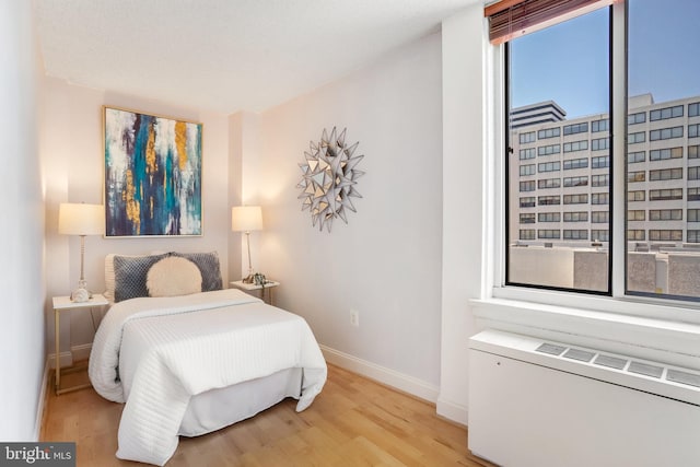 bedroom featuring radiator and light hardwood / wood-style floors