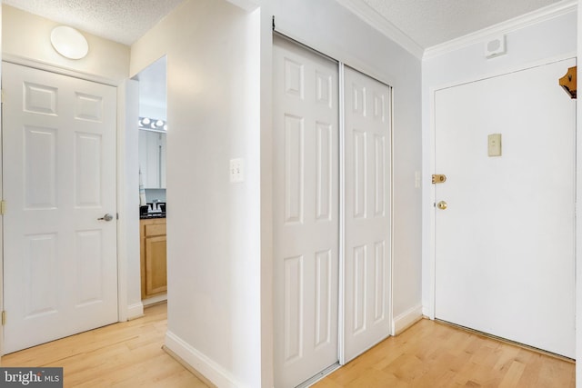 foyer with ornamental molding, a textured ceiling, and light wood-type flooring