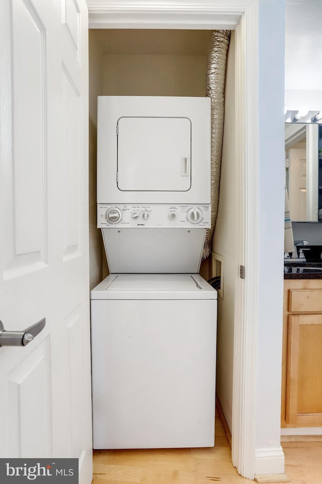 laundry room featuring light hardwood / wood-style flooring and stacked washer / dryer