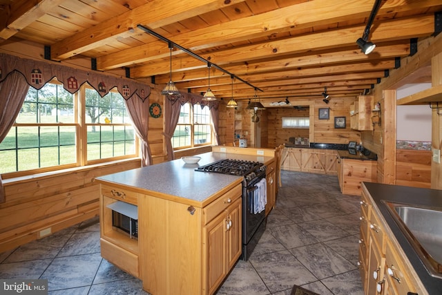 kitchen featuring dark tile patterned flooring, a healthy amount of sunlight, a center island, and gas stove