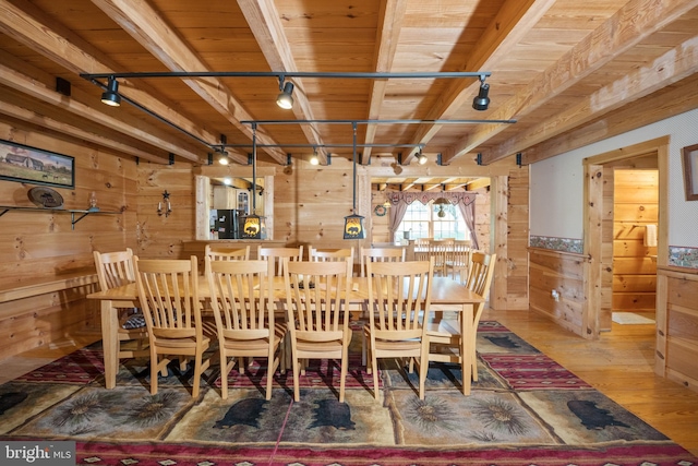 dining space featuring wooden ceiling, light hardwood / wood-style floors, beamed ceiling, track lighting, and wood walls