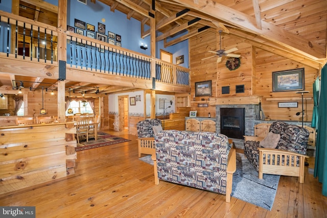 living room featuring a fireplace, wood walls, a high ceiling, and hardwood / wood-style floors