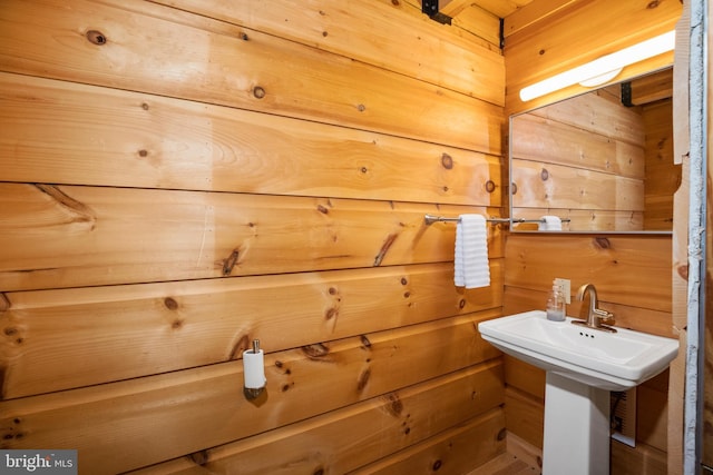 bathroom with wood walls and a sink