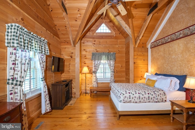 bedroom with lofted ceiling with beams, wooden walls, light wood-style flooring, and wooden ceiling