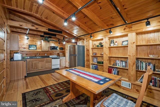 interior space with light wood-type flooring, wooden ceiling, rail lighting, sink, and wood walls