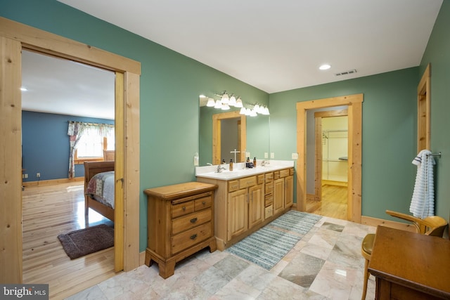 full bath with vanity, wood finished floors, baseboards, visible vents, and ensuite bathroom