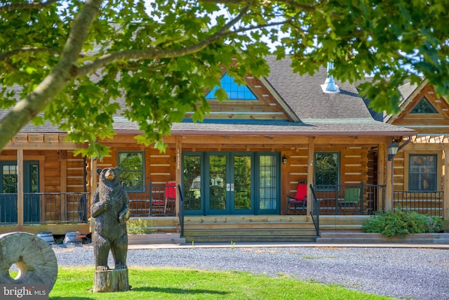 view of front facade with french doors, roof with shingles, covered porch, and log exterior