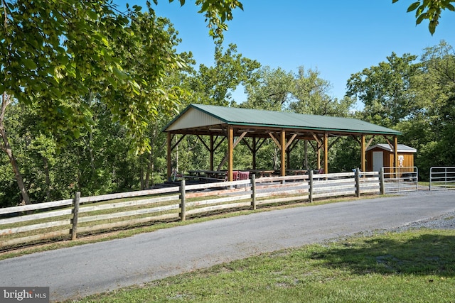 view of property's community featuring a detached carport, driveway, an outdoor structure, and fence