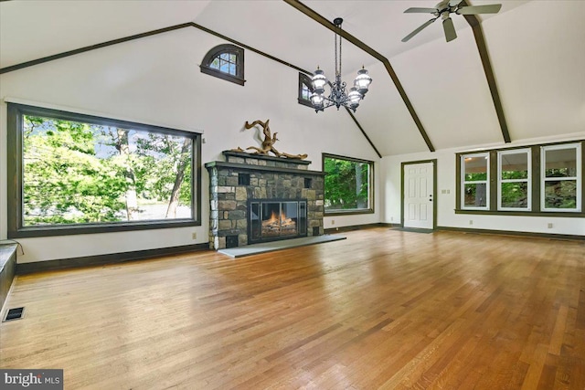 unfurnished living room with a fireplace, high vaulted ceiling, light hardwood / wood-style floors, and ceiling fan with notable chandelier