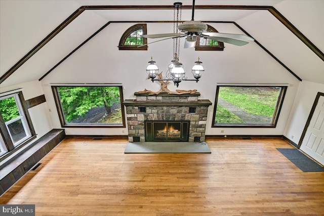 unfurnished living room with hardwood / wood-style flooring, ceiling fan with notable chandelier, a healthy amount of sunlight, and vaulted ceiling