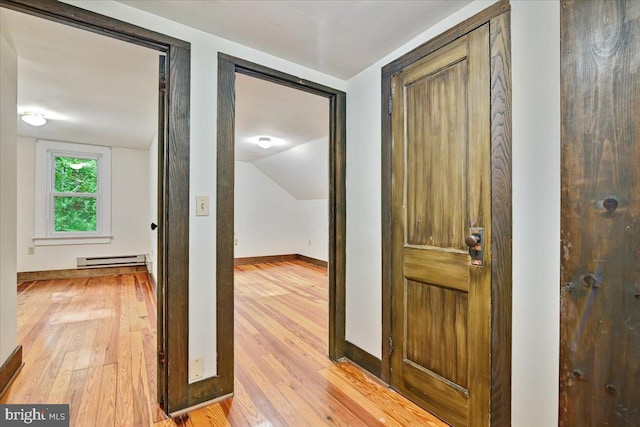 corridor with vaulted ceiling, light hardwood / wood-style flooring, and a baseboard radiator