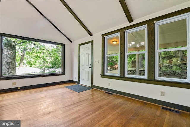 interior space featuring hardwood / wood-style floors and vaulted ceiling with beams