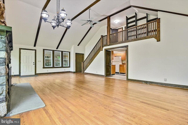 unfurnished living room with ceiling fan with notable chandelier, light hardwood / wood-style floors, a fireplace, and high vaulted ceiling