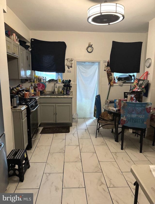 kitchen with sink, black gas stove, light tile patterned floors, and gray cabinets