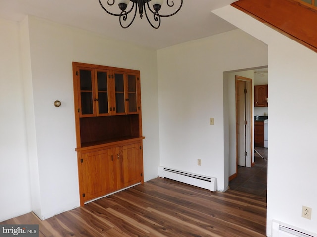 spare room with baseboard heating, an inviting chandelier, and dark hardwood / wood-style floors