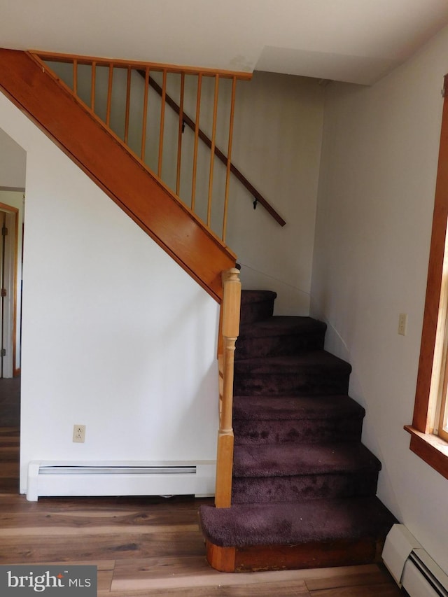 staircase featuring a baseboard radiator and wood finished floors