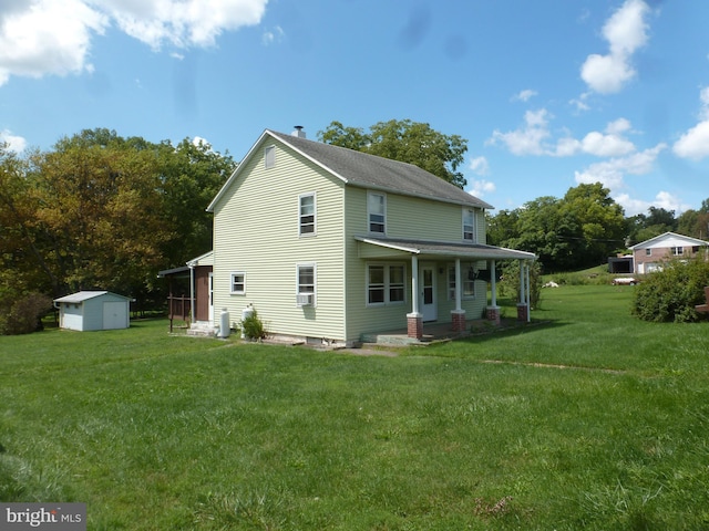 back of property with a storage shed, a yard, and covered porch