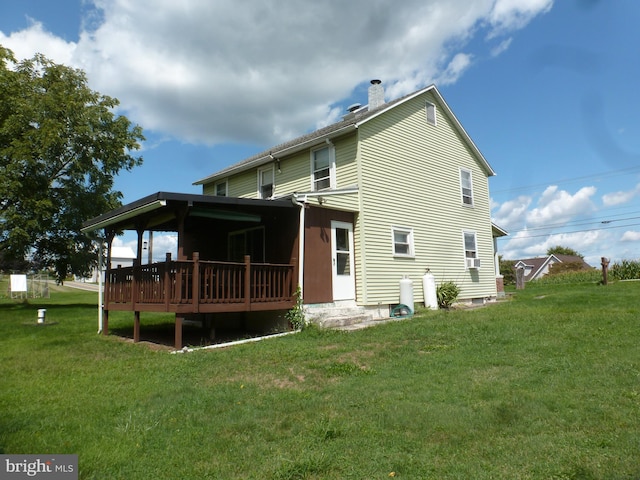 back of property featuring a wooden deck and a yard