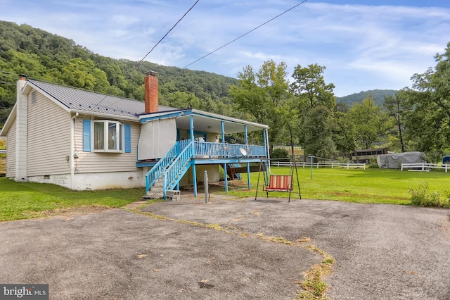 rear view of house featuring a porch, a mountain view, and a lawn