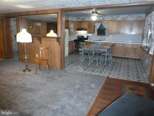 kitchen with sink, backsplash, gas range, decorative light fixtures, and wood walls