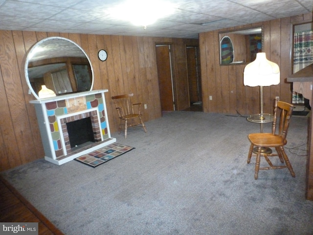 unfurnished living room featuring a brick fireplace, carpet, and wood walls