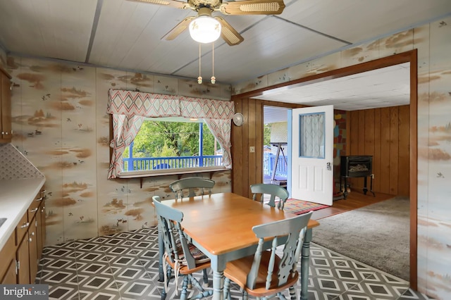 dining area featuring ceiling fan and wood walls