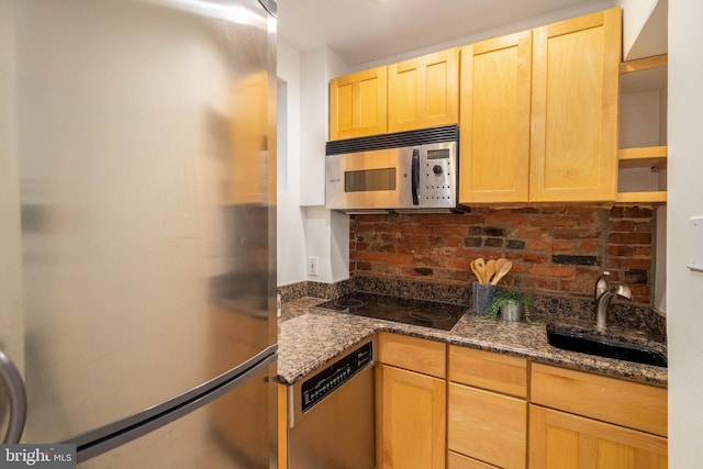 kitchen with sink, light brown cabinets, dark stone counters, and appliances with stainless steel finishes