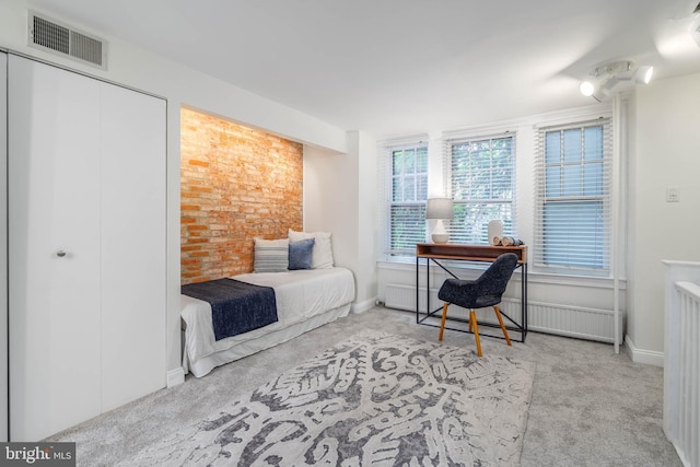 carpeted bedroom with brick wall and radiator heating unit