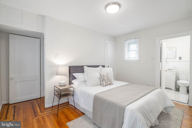 bedroom with ensuite bathroom and light hardwood / wood-style flooring