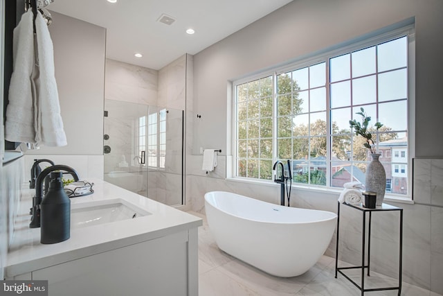 bathroom with visible vents, a soaking tub, marble finish floor, vanity, and a shower stall