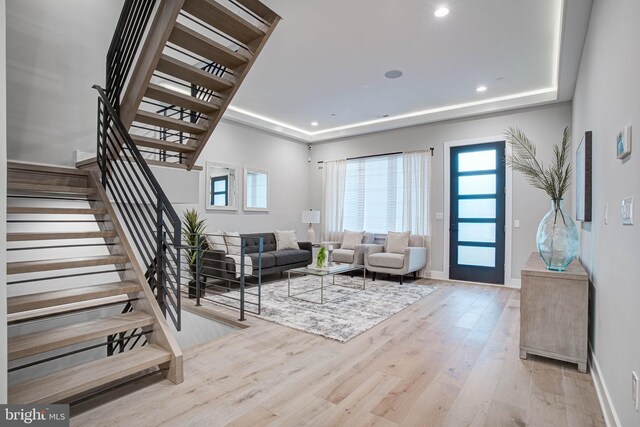 living room with a tray ceiling and light hardwood / wood-style floors