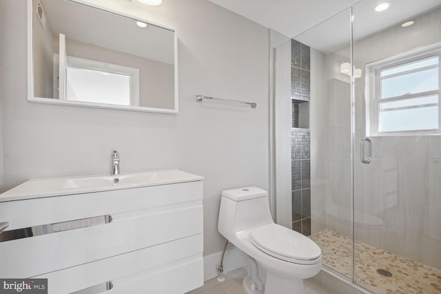 bathroom featuring a shower with shower door, toilet, and vanity