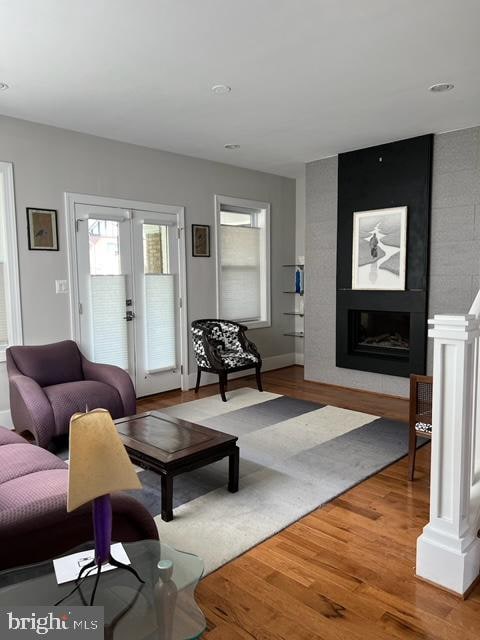 living room featuring a large fireplace, wood-type flooring, and french doors