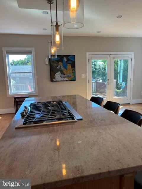 kitchen featuring stainless steel gas cooktop, a wealth of natural light, decorative light fixtures, and stone counters