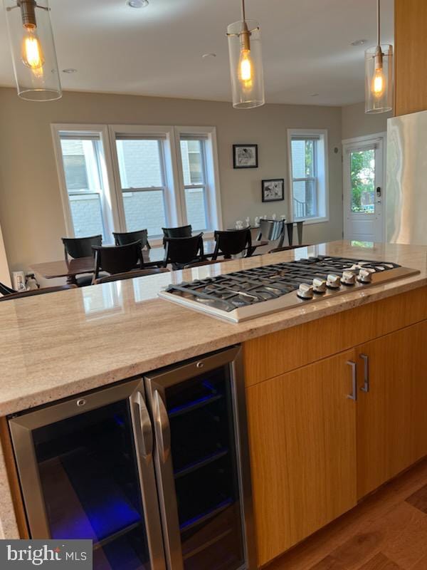 kitchen featuring stainless steel gas stovetop, wine cooler, decorative light fixtures, and light wood-type flooring