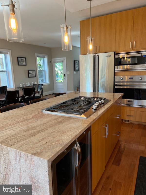 kitchen with a center island, hardwood / wood-style floors, pendant lighting, and stainless steel appliances