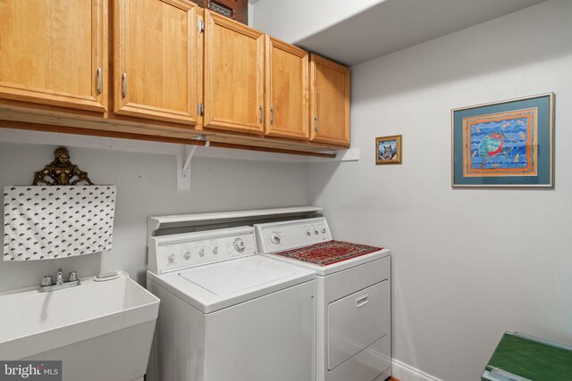 clothes washing area with washer and dryer, cabinets, and sink