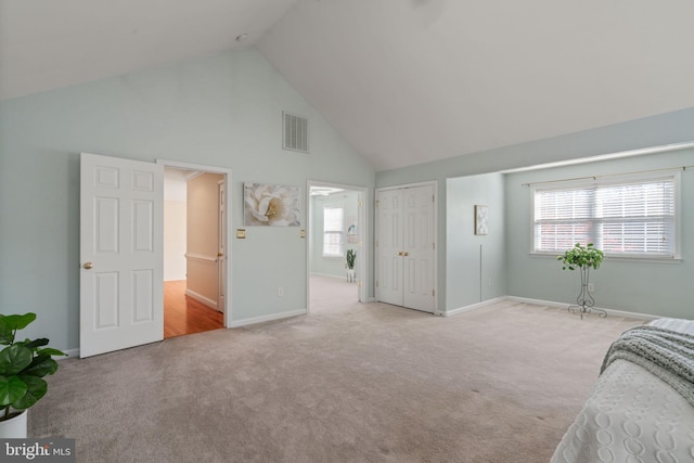 bedroom featuring ensuite bath, light colored carpet, high vaulted ceiling, and ceiling fan