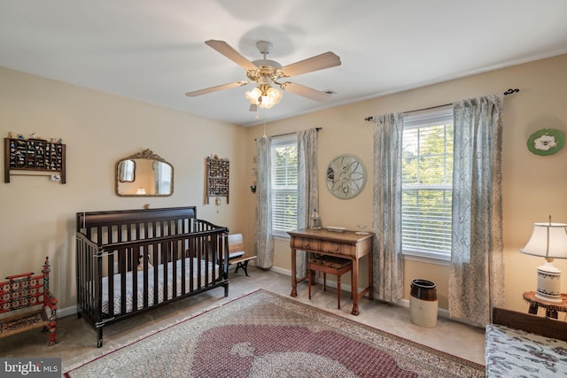 carpeted bedroom featuring a crib and ceiling fan