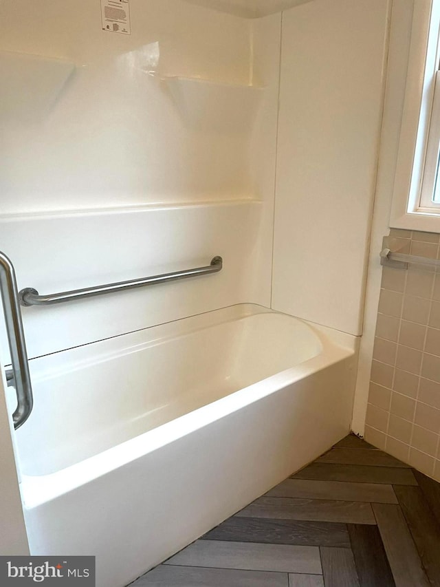 bathroom featuring washtub / shower combination and tile walls