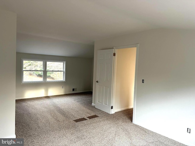 carpeted spare room with vaulted ceiling