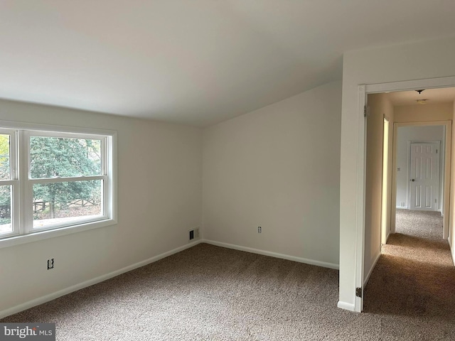 carpeted spare room featuring lofted ceiling